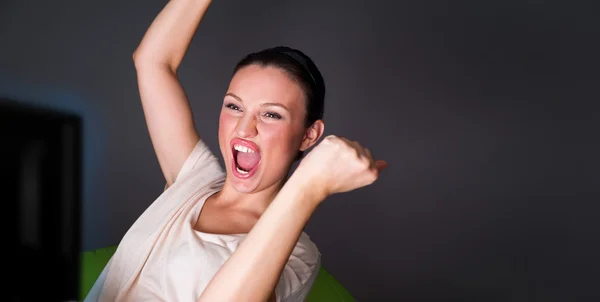 Young woman watching tv and having fun with lots of emotions — Stock Photo, Image