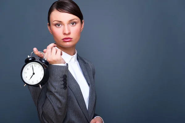 若いビジネス女性示す目覚まし時計 copys で灰色の背景 — ストック写真