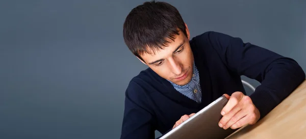 Close-up van een jonge lachende zakenman achter zijn bureau tegen grijs — Stockfoto