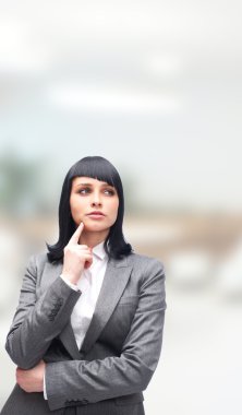 Caucasian woman thinking in looking pensive and happy in formal clothes while standing at her office clipart