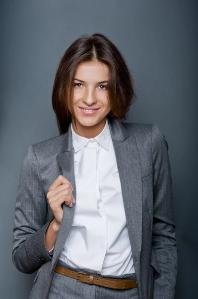 Portret van een mooie jonge zakenvrouw permanent tegen grijs CHTERGRO — Stockfoto