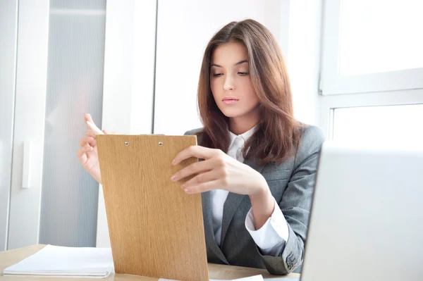 Porträt einer jungen Geschäftsfrau in einem Büro mit Dokumenten auf dem Arm — Stockfoto