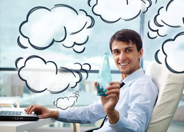 Young businessman drinking water sitting relaxed on armchair at his modern office. Blank cloud balloon overhead — Stock Photo, Image
