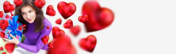 Donna deliziata aprire un regalo seduto sul sacchetto di fagioli a casa e belle forme di cuore rosso stanno volando intorno. Locandina concetto San Valentino — Foto Stock