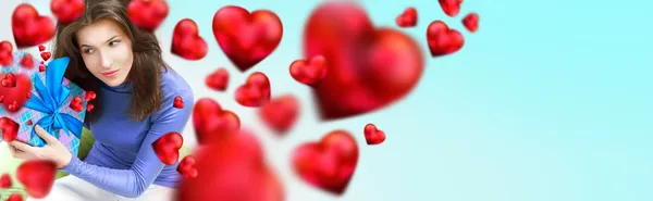Задоволена жінка відкриває подарунок, сидячи на бобовій сумці вдома і красиві червоні форми серця літають навколо. День святого Валентина концепт плакат — стокове фото