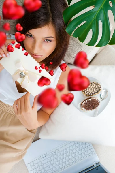 Retrato de jovem mulher bonita comendo bolos saborosos no Dia dos Namorados e corações gráficos estão voando em torno dela — Fotografia de Stock