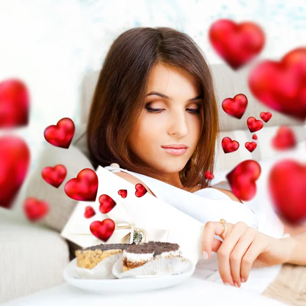 Ritratto di giovane bella donna che mangia gustose torte a San Valentino e cuori grafici volano intorno a lei — Foto Stock