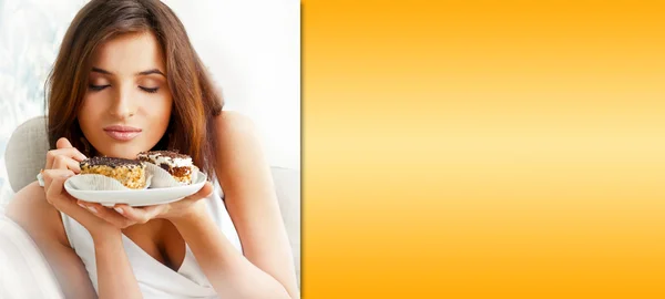 Jonge mooie vrouw met een taart. Close-up portret. zittend op de Bank bij haar thuis. bereid copyspace aan de rechterkant van de afbeelding — Stockfoto