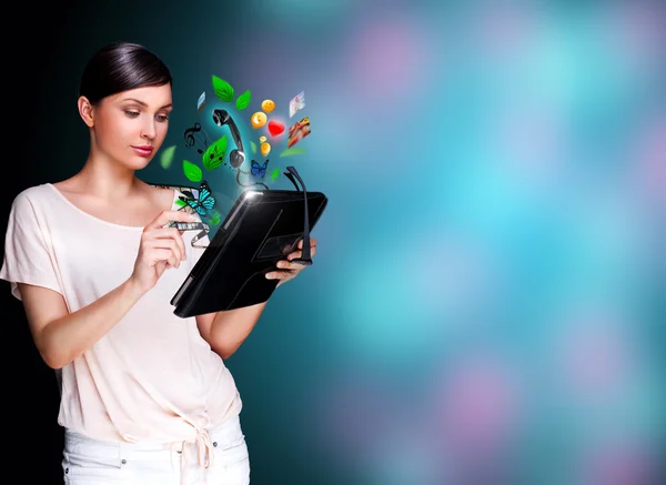 Poster portrait of young beautiful woman holding her universal device - tablet pc. Lots of things are appearing from the display. Universality of modern devices concept — 스톡 사진
