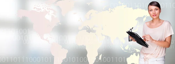Retrato de jovem mulher em pé na frente do mapa do mundo grande e usando seu computador tablet — Fotografia de Stock