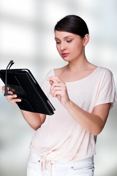 Πορτρέτο του νέα όμορφη γυναίκα που κρατά υπολογιστή δισκίο και γυαλιά που είναι χαμογελώντας στέκεται στο γραφείο της — Φωτογραφία Αρχείου