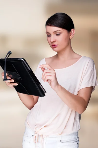 Портрет молодой красивой женщины с планшетным компьютером и очками, улыбающейся стоя у себя в офисе — стоковое фото