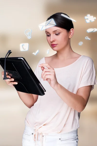 Une femme d'affaires avec des icônes de ses affaires flottant autour de sa tête. Portrait de jolie femme travaillant avec sa tablette PC regardant l'écran et souriant. Affaires quotidiennes en ligne — Photo