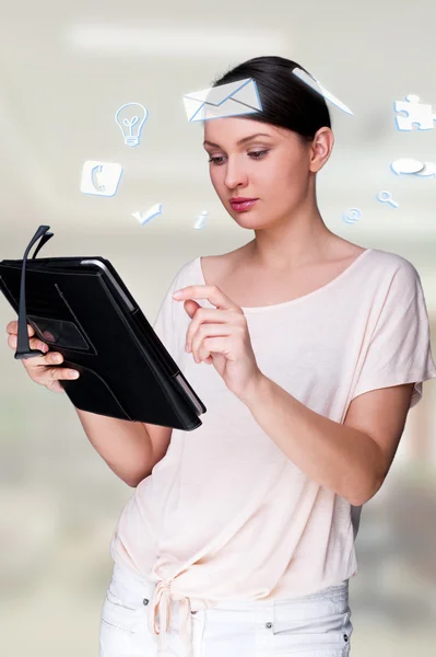 A business woman with icons of her affairs floating around her head. Portrait of pretty woman working with her tablet pc looking at screen and smiling. Daily affairs online — Stock Photo, Image