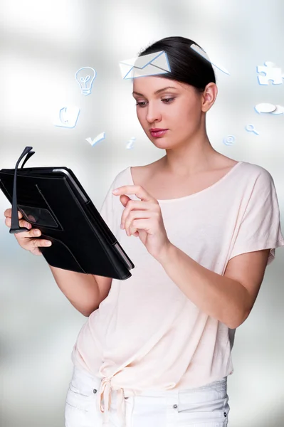 A business woman with icons of her affairs floating around her head. Portrait of pretty woman working with her tablet pc looking at screen and smiling. Daily affairs online — Stock Photo, Image