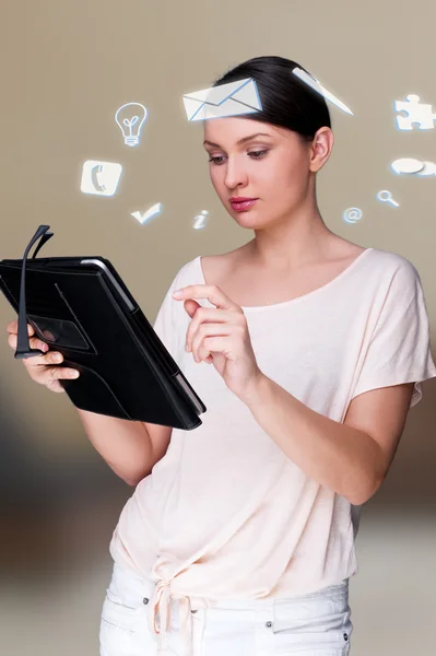 A business woman with icons of her affairs floating around her head. Portrait of pretty woman working with her tablet pc looking at screen and smiling. Daily affairs online — Stock Photo, Image