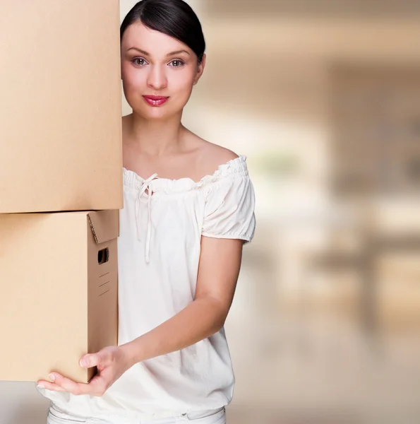 Усміхнена жінка тримає коробки після переїзду дивиться на камеру — стокове фото