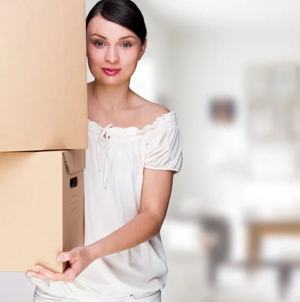 Усміхнена жінка тримає коробки після переїзду дивиться на камеру — стокове фото
