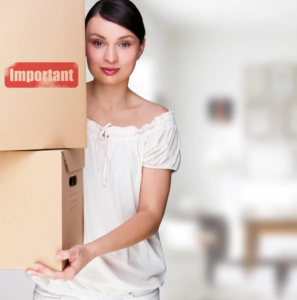 Μια γυναίκα που κρατά ένα κουτί μέσα κτίριο γραφείων ή ένα εγχώριο εσωτερικό. πακέτο σημάδι στο κουτί — Φωτογραφία Αρχείου