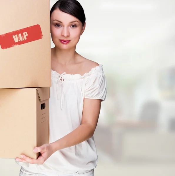 一个女人抱着一个盒子里面办公大楼或家庭内部。包登录框 — 图库照片