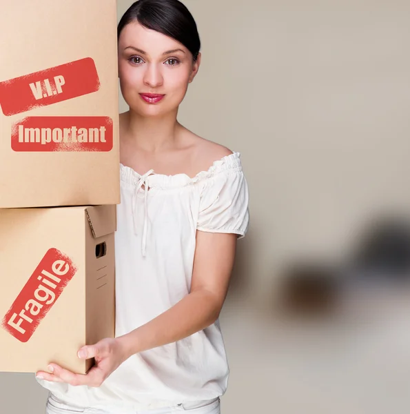 Женщина, держащая коробку внутри офисного здания или интерьера дома. Знак пакета на коробке — стоковое фото