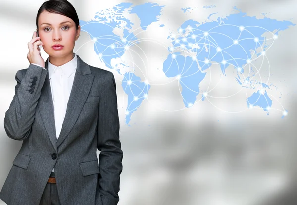 Portrait of beautiful business woman on the phone at her office near transparent virtual world map — Stock Photo, Image