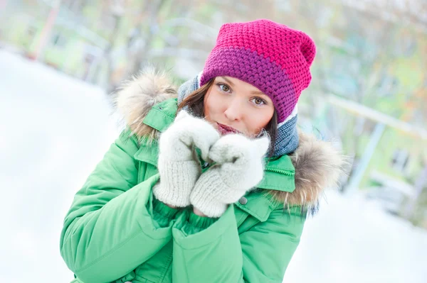 Vintern kvinnan i snön titta på kameran utanför på snöar kall vinterdag. porträtt kaukasiska kvinnlig modell utanför i första snön — Stockfoto