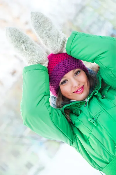 Jovem mulher bonita vestindo roupas de inverno e jogando ao ar livre. Segurando suas mãos perto de sua cabeça e mostra coelho engraçado — Fotografia de Stock