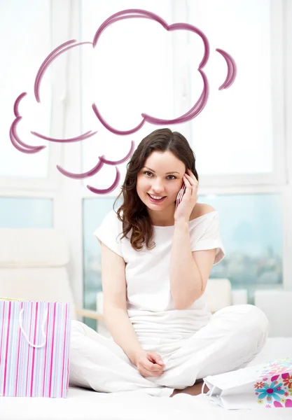 Portrait of young beautiful awake woman with gifts on bed at bedroom. Talking with her boyfriend by mobile phone. Cloud balloon overhead — Stock Fotó