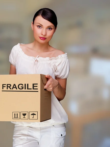 A woman holding a box inside office building or home interior. Package sign on box — Stock Photo, Image