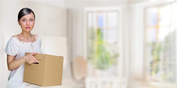 Улыбающаяся женщина у себя дома держит коробки. Она переезжает в свой новый дом. Концепция ипотеки — стоковое фото