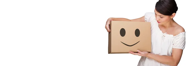 Attractive woman with box making a removal. Smile face illustrated on box. Easy, happy carefree moving concept — Stock Photo, Image