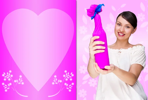 Portrait of young pretty woman holding bottle of prefect wine in gift decorative package against love valentine background with heart shape — Stock Photo, Image