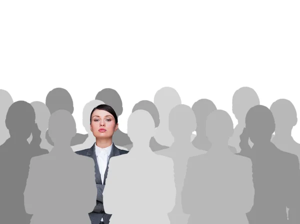 Leader concept. Portrait of young business woman standing with hands folded and grey silhouettes are standing around her — Stock Photo, Image