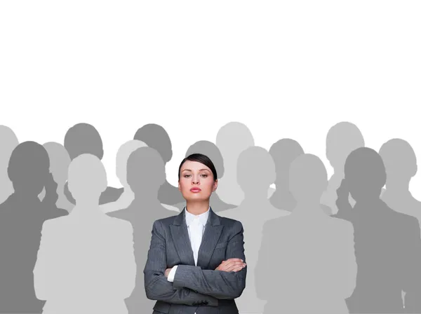 Leader concept. Portrait of young business woman standing with hands folded and grey silhouettes are standing around her — Stock Photo, Image