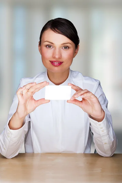 Junge Geschäftsfrau zeigt ihre Visitenkarte - sitzt in ihrem Büro — Stockfoto