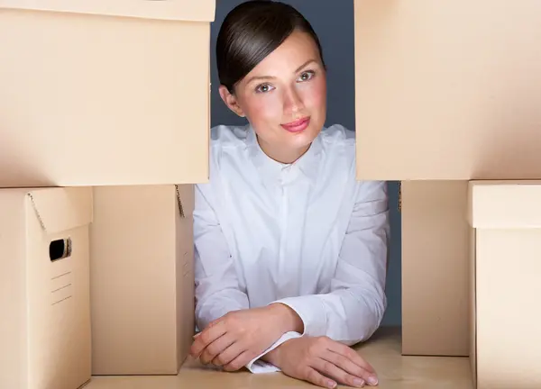 Retrato de una joven rodeada de muchas cajas. Mucho concepto de trabajo — Foto de Stock