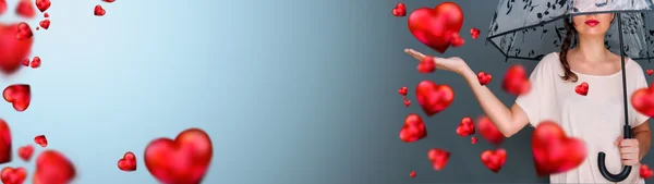 Jonge modieuze vrouw bedrijf paraplu permanent tegen de grijze achtergrond rode harten zweven rond haar. liefde regen op saint valentine concept — Stockfoto