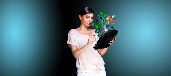 Poster portrait of young beautiful woman holding her universal device - tablet pc. Lots of things are appearing from the display. Universality of modern devices concept — Stock Photo, Image