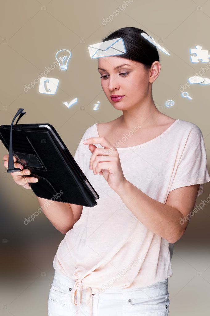 A business woman with icons of her affairs floating around her head. Portrait of pretty woman working with her tablet pc looking at screen and smiling. Daily affairs online