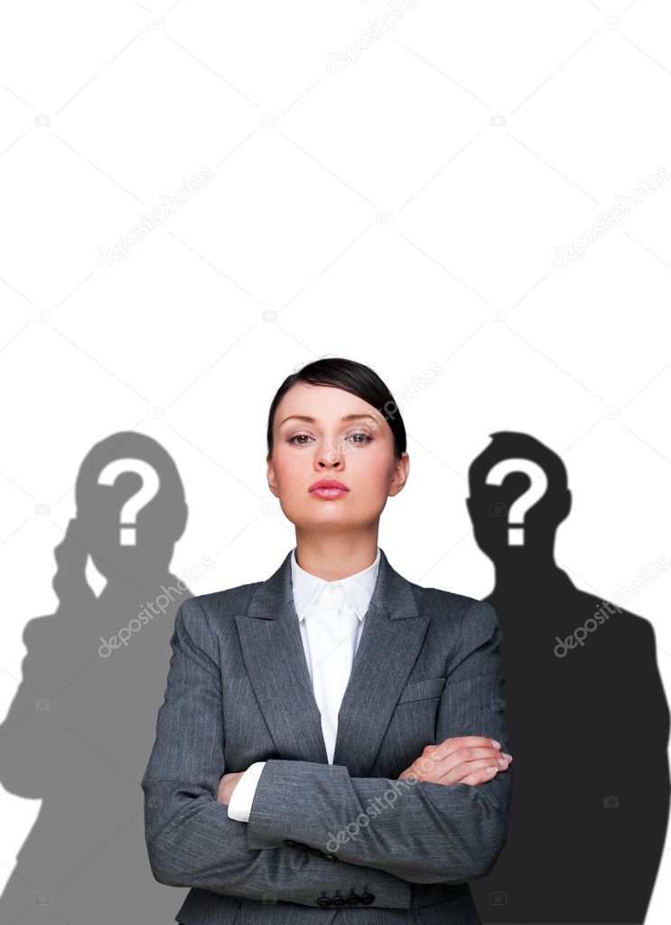 Leader concept. Portrait of young businesswoman standing with hands folded and grey silhouettes are standing around her