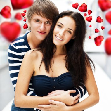 Portrait of young couple walking together at airport hall with their luggage. They are very happy to fly to warm country on holidays. Hearts around them. Valentine concept clipart