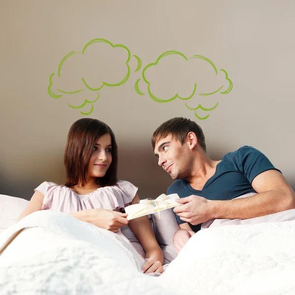成人对夫妇，他们在他们的公寓和贺卡给他的女朋友的男人的床上躺的特写画像。在为您的文本照片的顶部的空白气球。未来的规划概念 — 图库照片