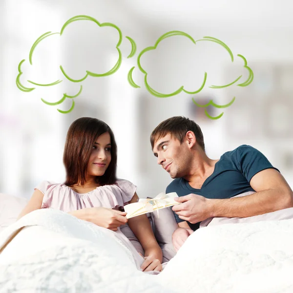 Detailní portrét dospělého páru ležící na posteli v jejich bytě a muž dává pohlednici se svou přítelkyní. prázdná bublina v horní části fotografie pro váš text. plánování budoucí koncepce — Stock fotografie