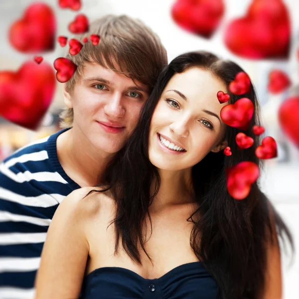 Närbild av ungt par allomfattande och mycket glad att vara tillsammans. Alla hjärtans koncept. röda hjärtan flyger runt dem. — Stockfoto