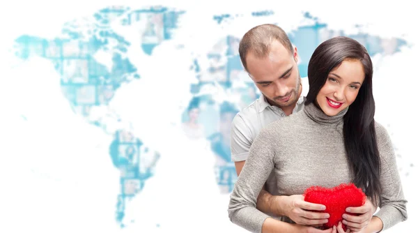 Porträt eines jungen Paares, das rote Herzen umarmt und hält. gegen Weltkarte mit Foto von — Stockfoto