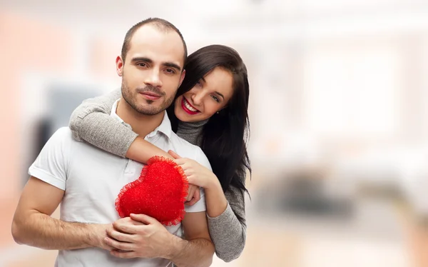 Portrait de jeune couple au cœur rouge debout à la maison et embrassant — Photo