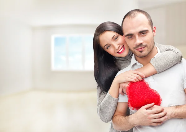 Genç bir çift ile onların evde duran ve kucaklayan kırmızı kalp portresi — Stok fotoğraf