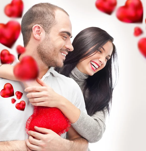 Schönes junges Liebespaar, das sich vor weißem Hintergrund umarmt und um sie herum viele rote Herzen fliegen — Stockfoto