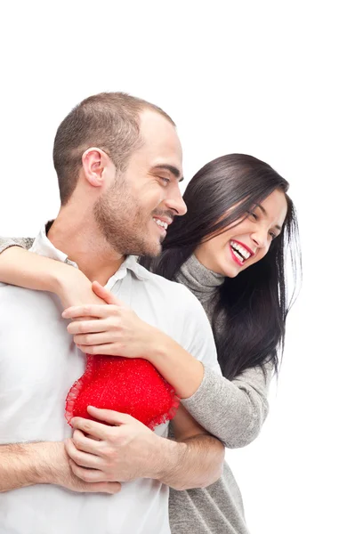Happy young adult couple with red heart on white background, embracing and laughing — Stock Photo, Image